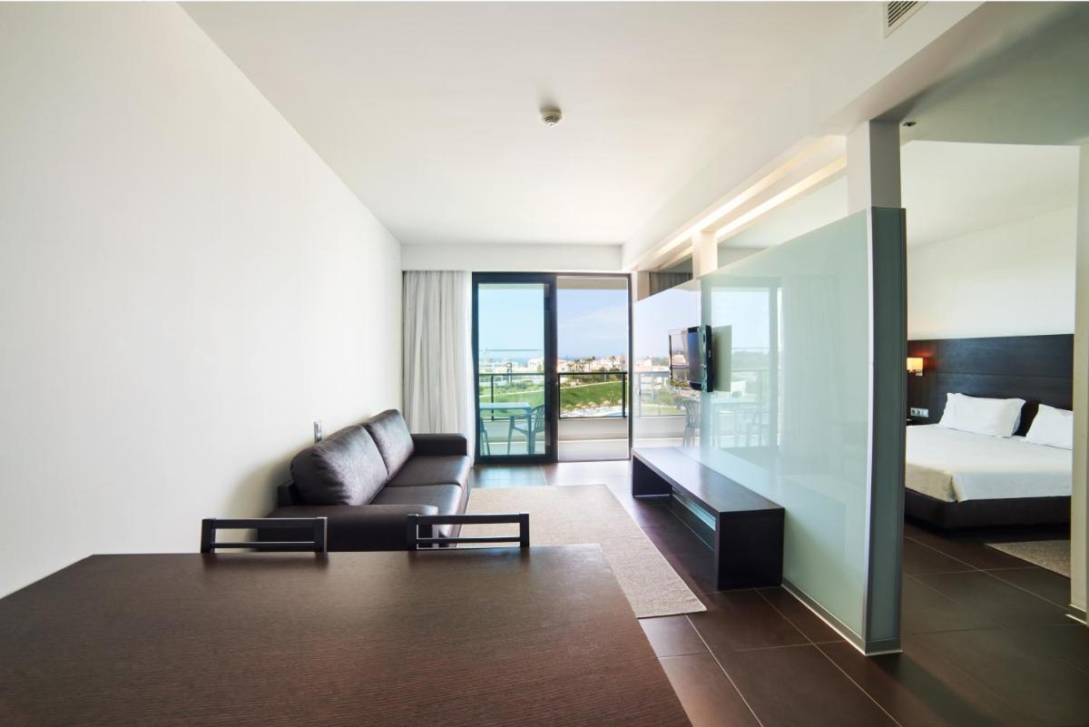 uma sala de estar com uma cama e um sofá em RR Alvor Baía Resort em Alvor uma sala de estar com uma cama e um sofá em RR Alvor Baía Resort em Alvor