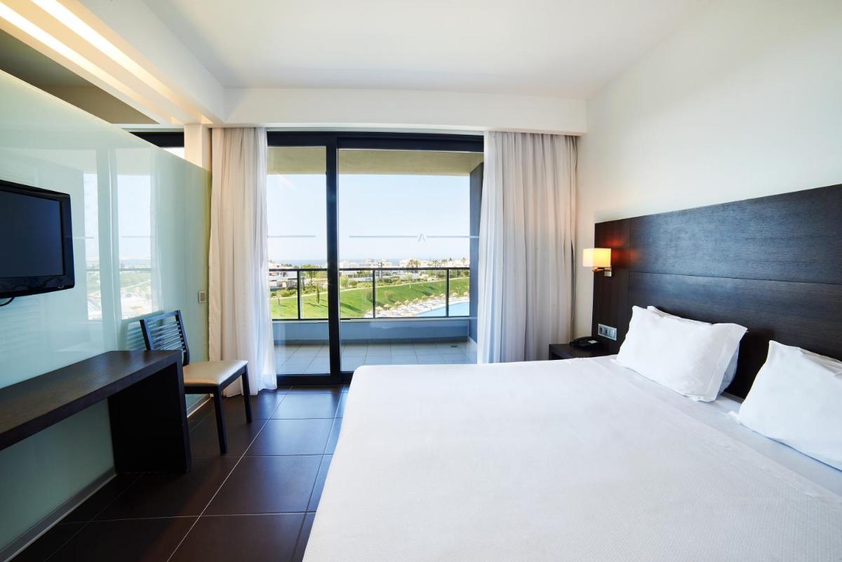 um quarto de hotel com uma cama grande e uma varanda em RR Alvor Baía Resort em Alvor mais 41 fotografias
