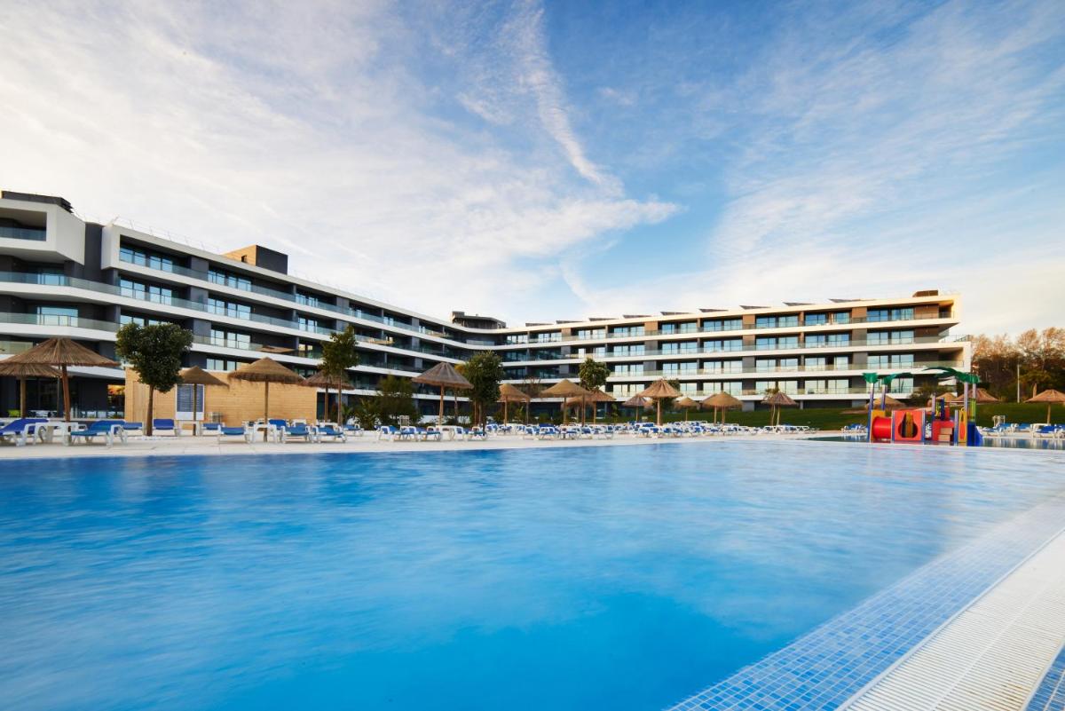 uma grande piscina em frente a um hotel em RR Alvor Baía Resort em Alvor uma grande piscina em frente a um hotel em RR Alvor Baía Resort em Alvor