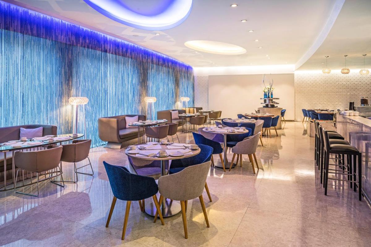 a restaurant with tables and chairs and a bar at The Park New Delhi in New Delhi a restaurant with tables and chairs and a bar at The Park New Delhi in New Delhi