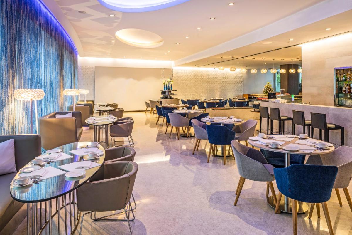 a restaurant with tables and chairs and a bar at The Park New Delhi in New Delhi a restaurant with tables and chairs and a bar at The Park New Delhi in New Delhi