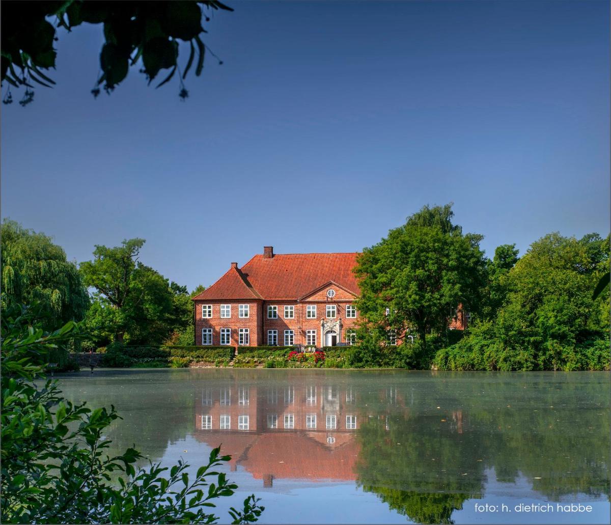 ein großes rotes Backsteinhaus neben einem See in der Unterkunft Herrenhaus Borghorst in Osdorf