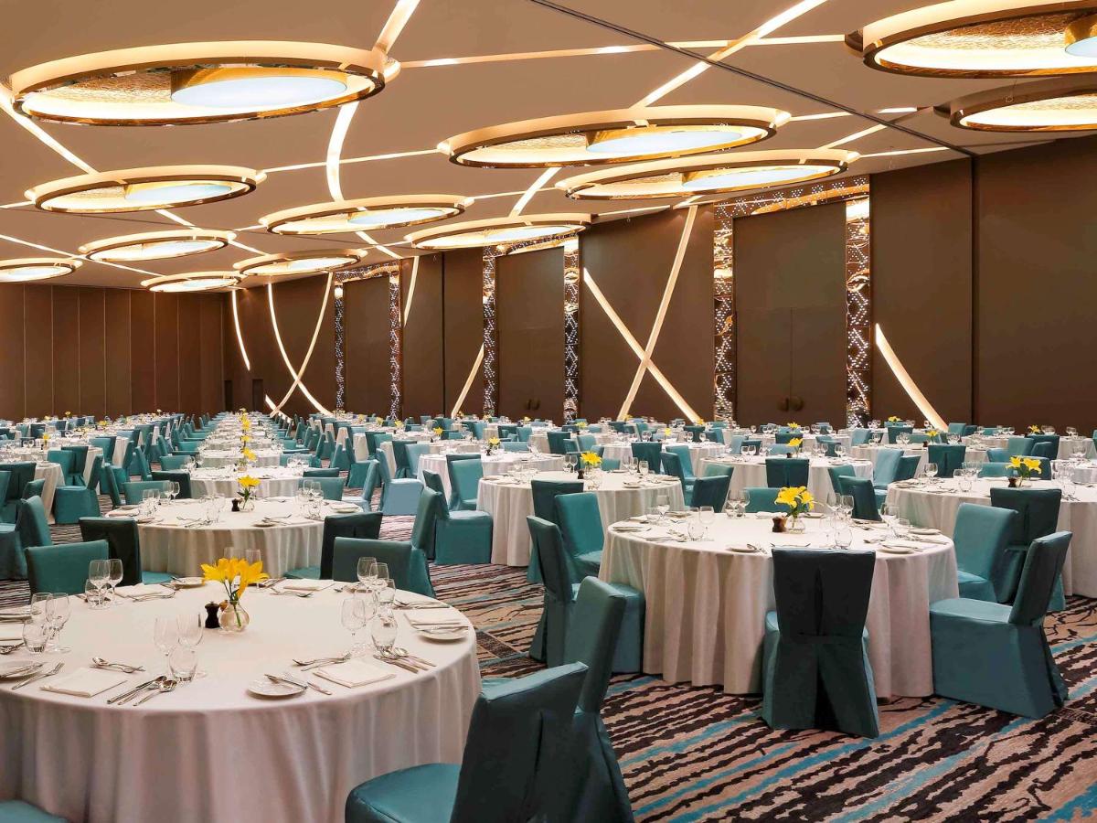a banquet hall with white tables and green chairs at Novotel New Delhi Aerocity in New Delhi