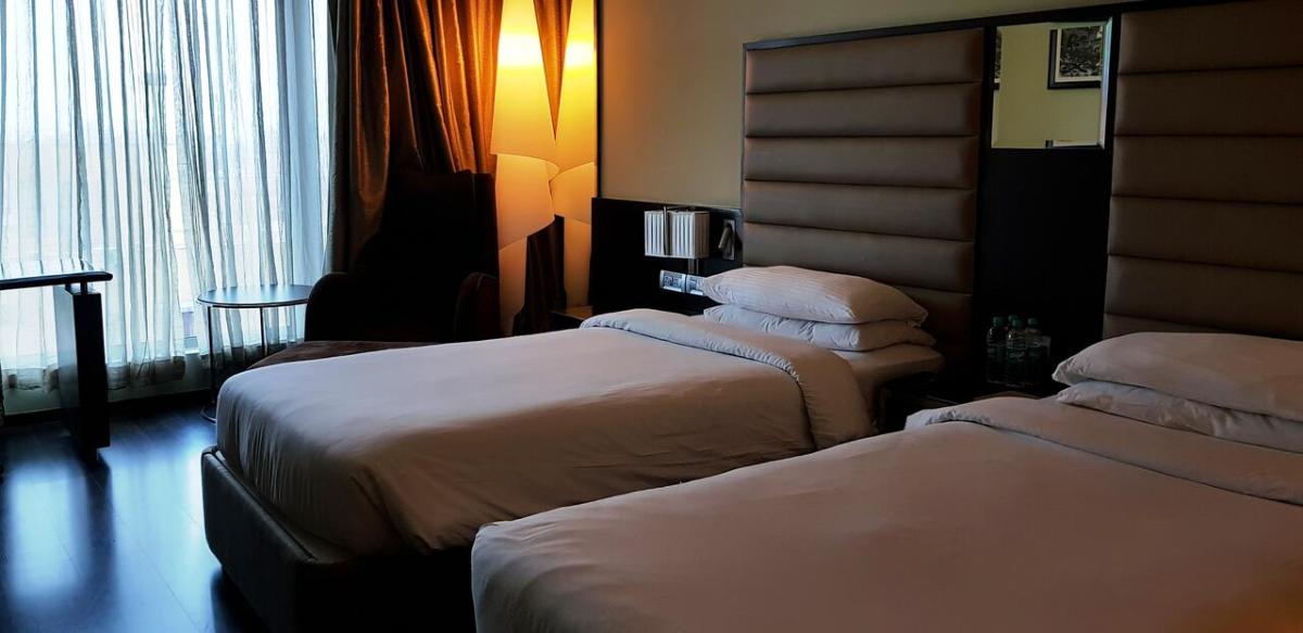 a hotel room with two beds and a window at Vivanta Hyderabad, Begumpet in Hyderabad a hotel room with two beds and a window at Vivanta Hyderabad, Begumpet in Hyderabad