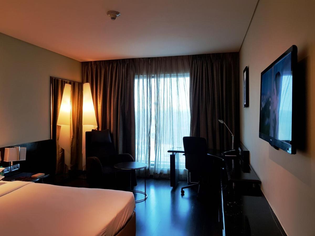 a hotel room with a bed and a desk and a television at Vivanta Hyderabad, Begumpet in Hyderabad a hotel room with a bed and a desk and a television at Vivanta Hyderabad, Begumpet in Hyderabad