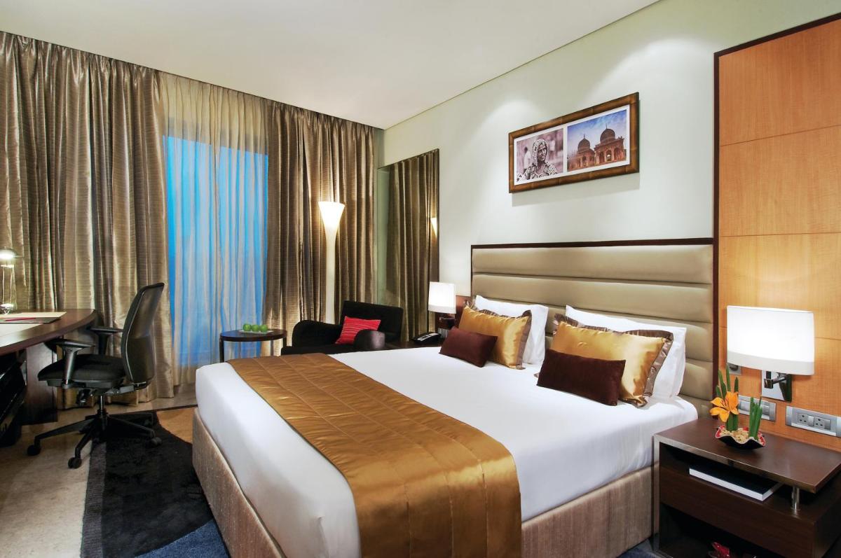 a hotel room with a large bed and a desk at Vivanta Hyderabad, Begumpet in Hyderabad a hotel room with a large bed and a desk at Vivanta Hyderabad, Begumpet in Hyderabad