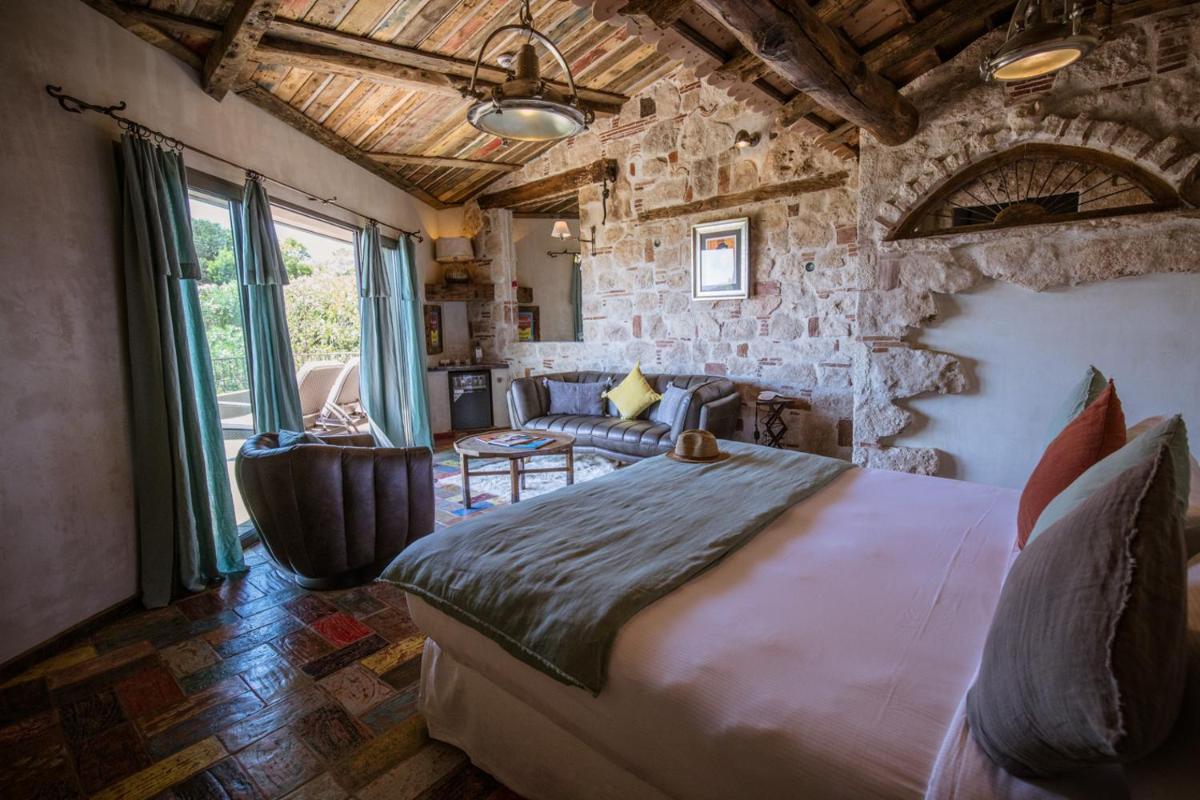 une chambre avec un grand lit et un mur en pierre dans l'établissement U Capu Biancu, à Bonifacio 121 autres photos