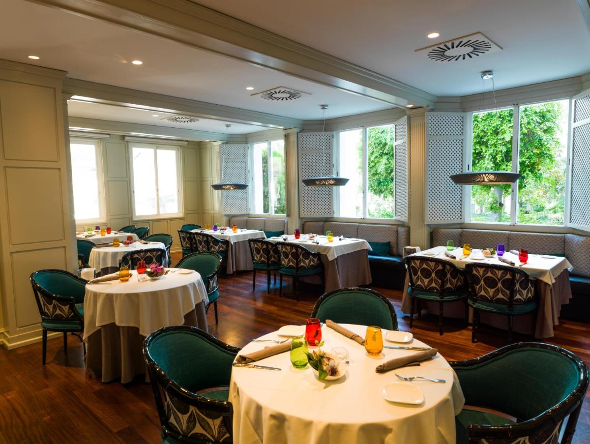Un comedor con mesas y sillas y ventanas. en Aparthotel Monarque Sultán, en Marbella