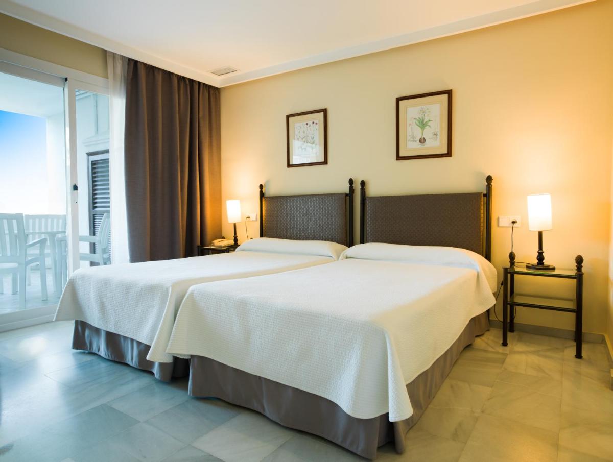 Una habitación de hotel con dos camas y balcón. en Aparthotel Monarque Sultán, en Marbella