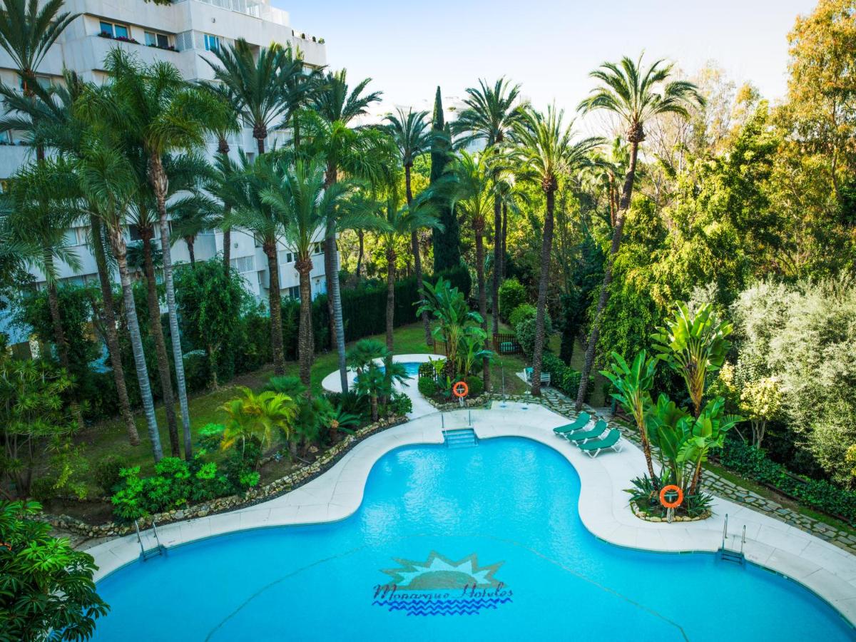 una vista aérea de una piscina en un complejo con palmeras en Aparthotel Monarque Sultán, en Marbella
