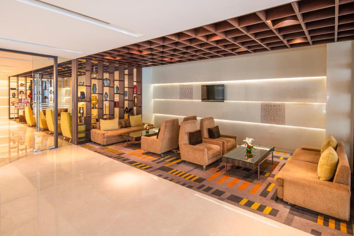 a lobby with couches and chairs and a television at Holiday Inn Mumbai International Airport by IHG in Mumbai