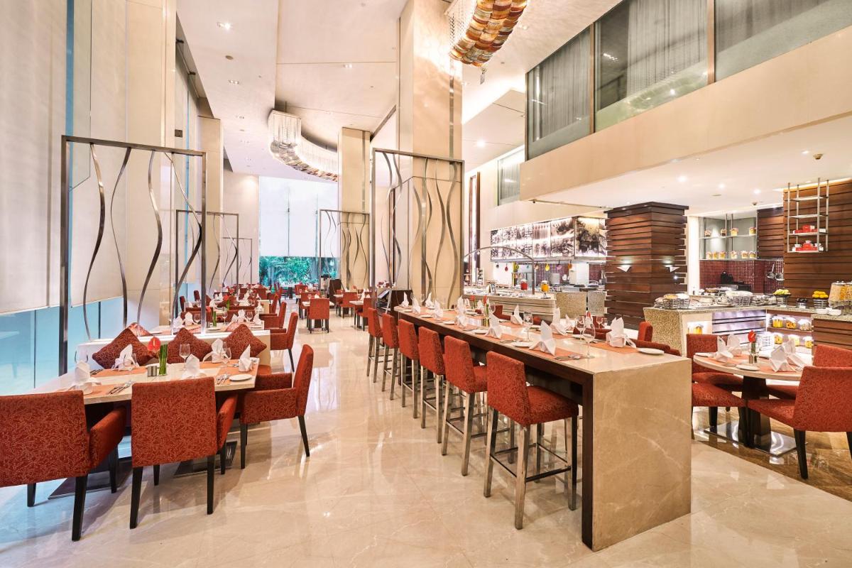 a dining room with tables and chairs in a restaurant at Holiday Inn Mumbai International Airport by IHG in Mumbai