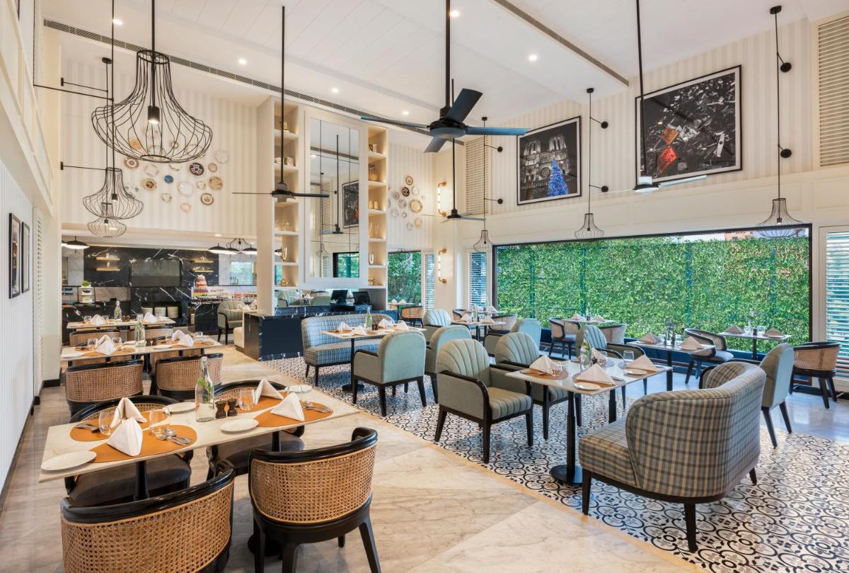 a restaurant with tables and chairs and a large window at The Residency Towers Puducherry in Puducherry