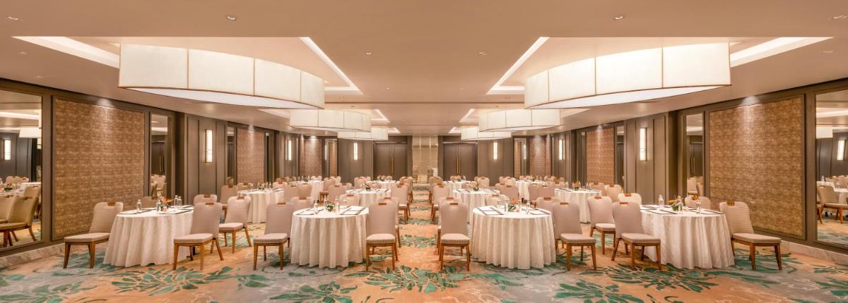 a banquet hall with white tables and chairs and chandeliers at The Residency Towers Puducherry in Puducherry