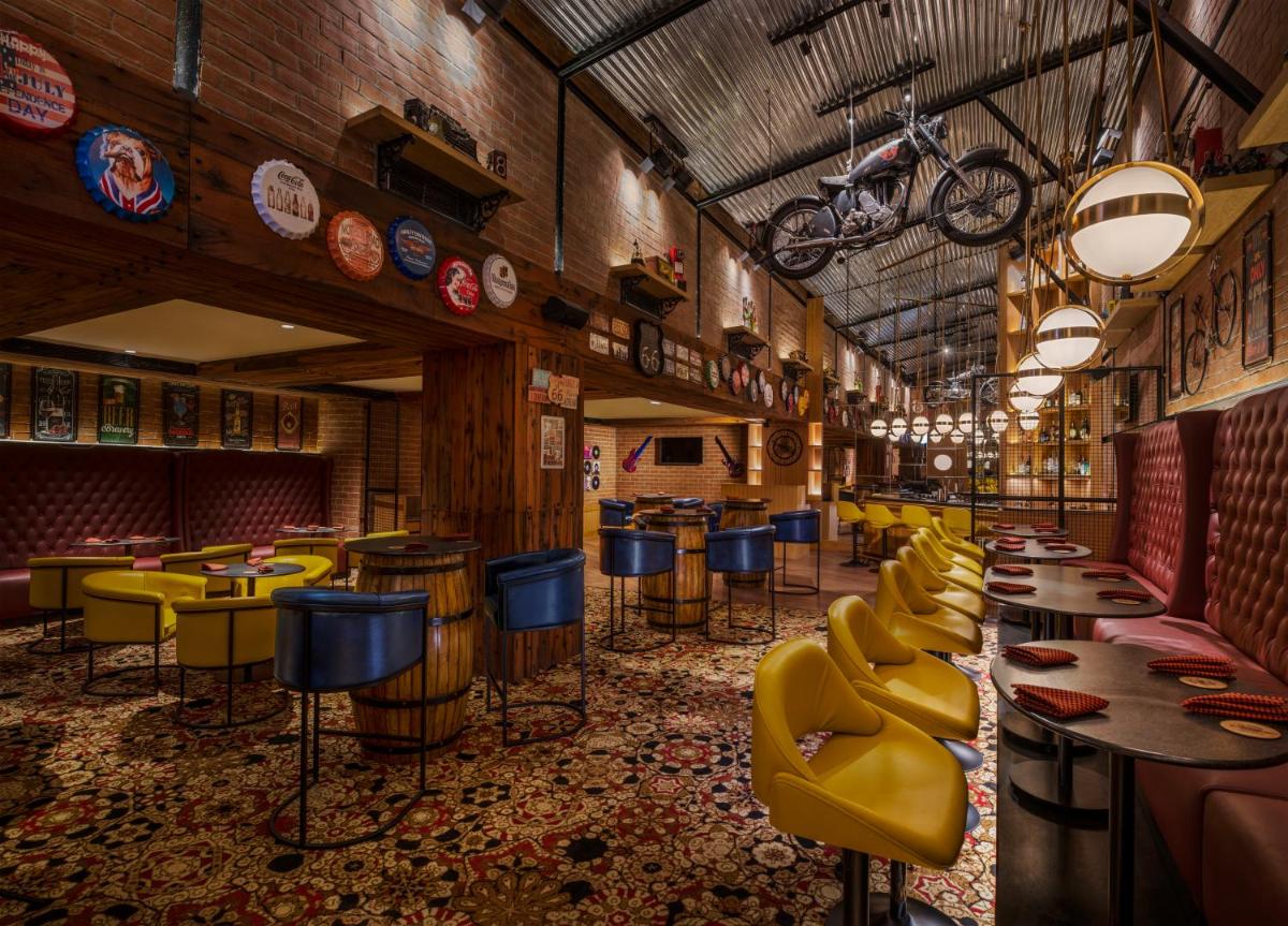 a bar with yellow chairs and tables in a restaurant at The Residency Towers Puducherry in Puducherry