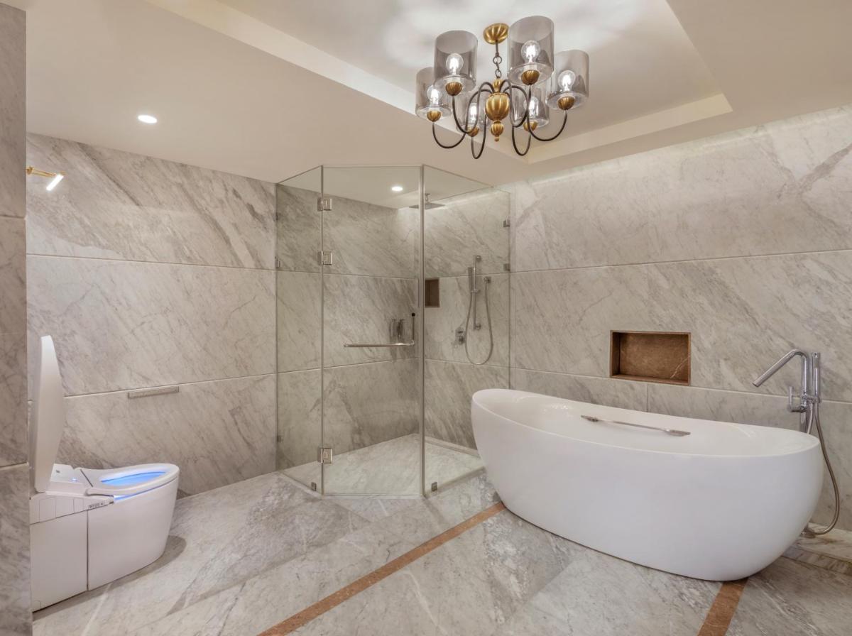 a bathroom with a tub and a shower and a chandelier at The Residency Towers Puducherry in Puducherry
