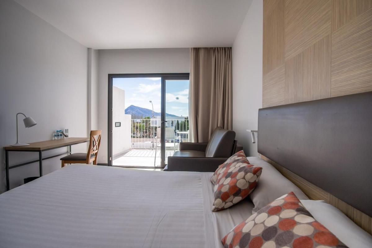Una habitación de hotel con una cama, un escritorio y una silla. en Hotel Cap Negret, en Altea
