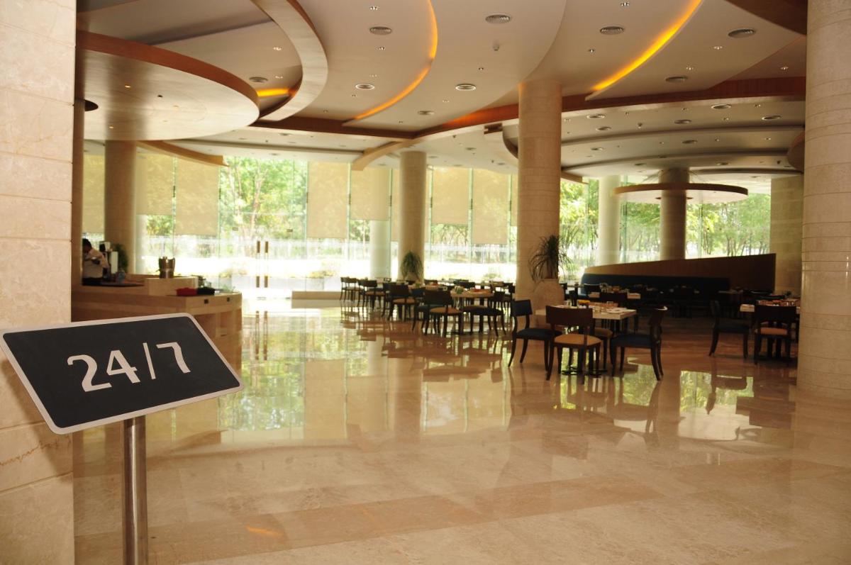 a restaurant with tables and chairs in a building at The Lalit Chandigarh in Chandīgarh