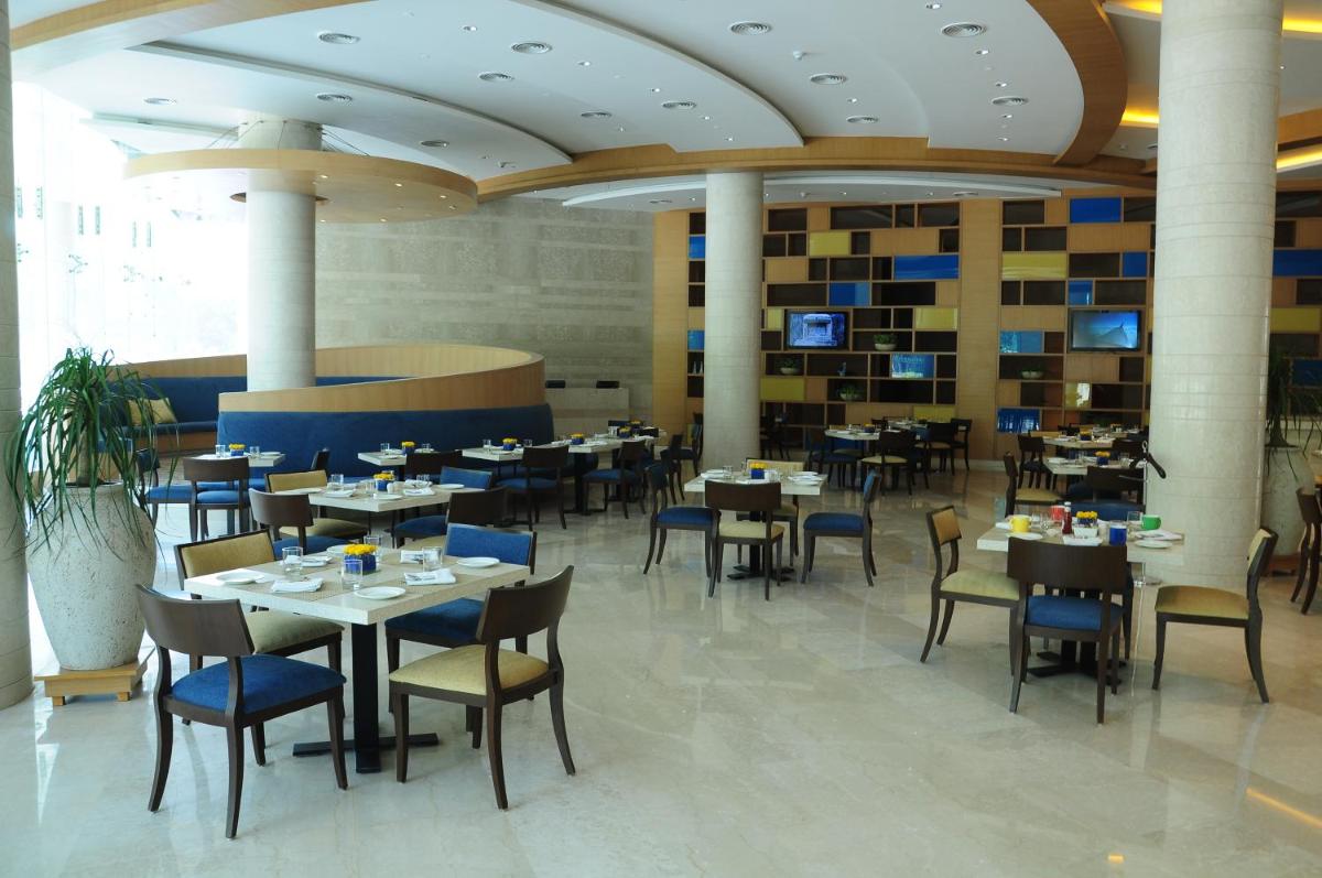 a dining room with tables and chairs in a building at The Lalit Chandigarh in Chandīgarh