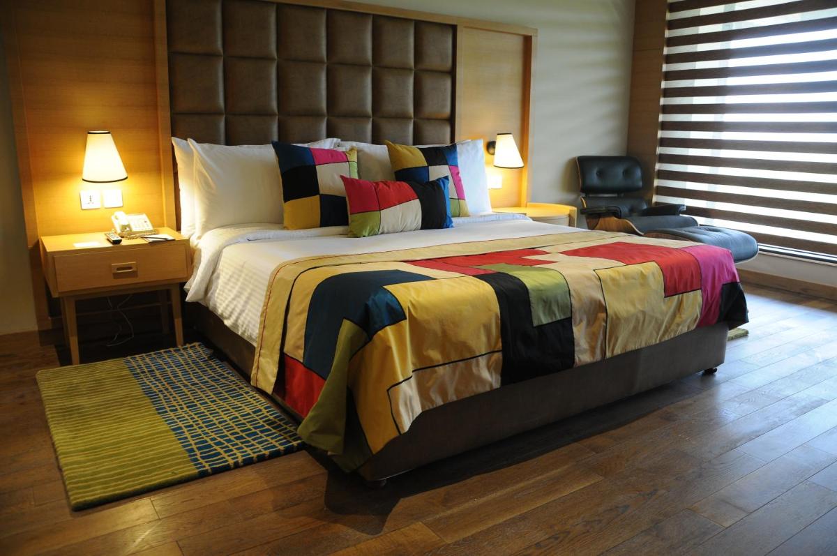 a bedroom with a large bed with a large headboard at The Lalit Chandigarh in Chandīgarh