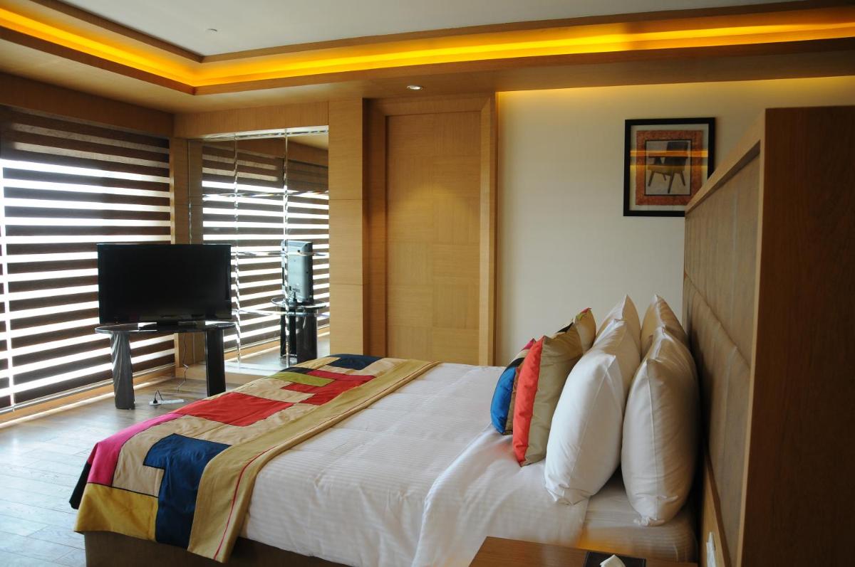 a bedroom with a bed and a flat screen tv at The Lalit Chandigarh in Chandīgarh