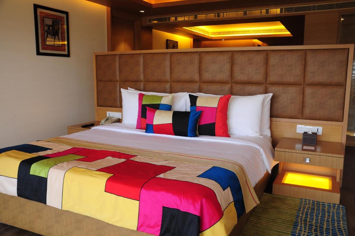 a bedroom with a large bed with colorful pillows at The Lalit Chandigarh in Chandīgarh