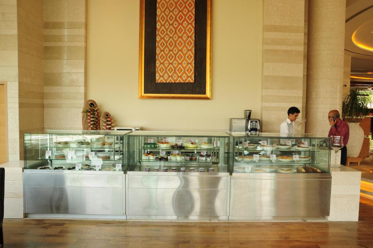 two people standing behind a display case in a restaurant at The Lalit Chandigarh in Chandīgarh