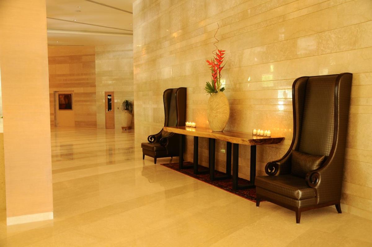 a lobby with a table and two chairs and a vase at The Lalit Chandigarh in Chandīgarh