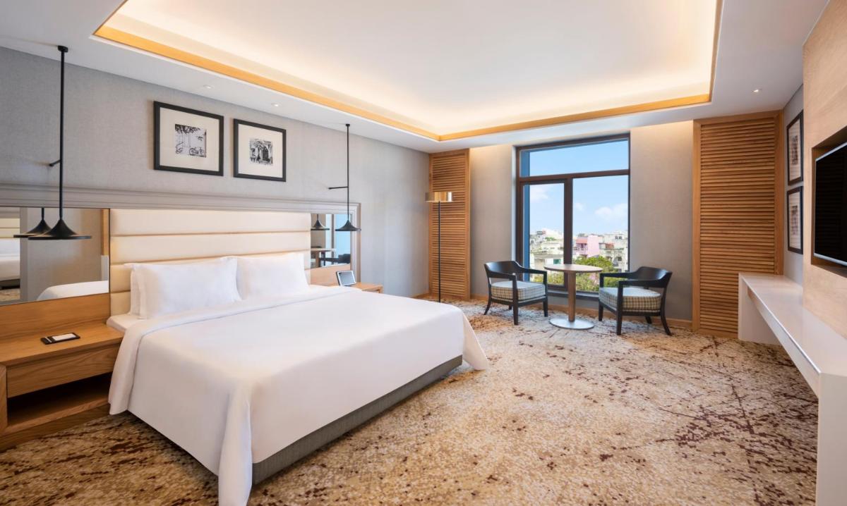 a bedroom with a white bed and a table and chairs at The Residency Towers Puducherry in Puducherry