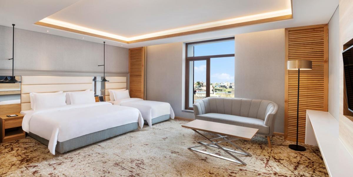 a hotel room with two beds and a chair at The Residency Towers Puducherry in Puducherry