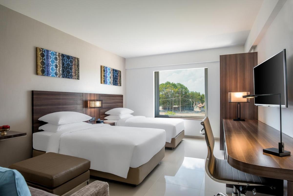 a hotel room with two beds and a television at The Residency Towers, Rameswaram in Rāmeswaram