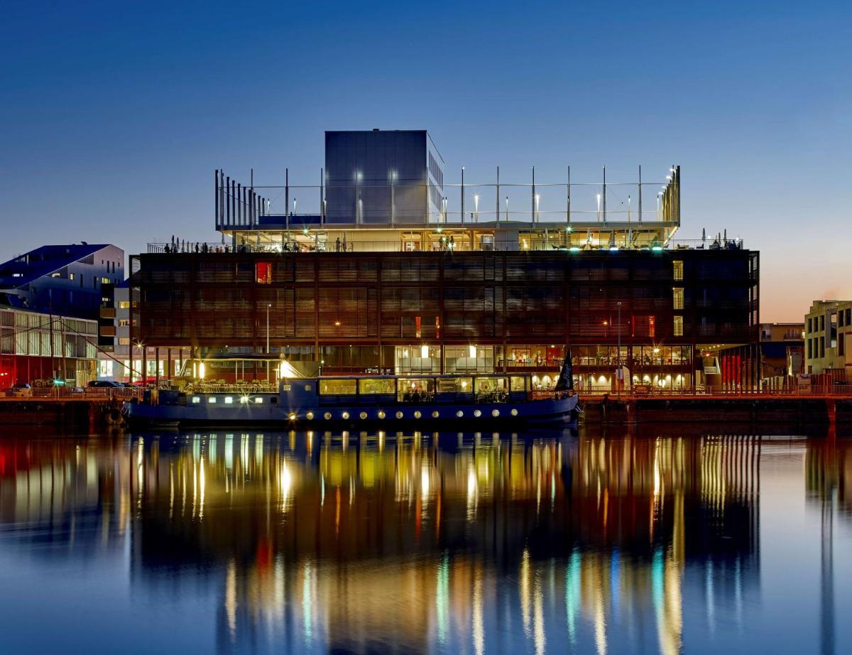 un grand bâtiment au bord de l'eau avec ses lumières allumées dans l'établissement Radisson Blu Hotel Bordeaux, à Bordeaux