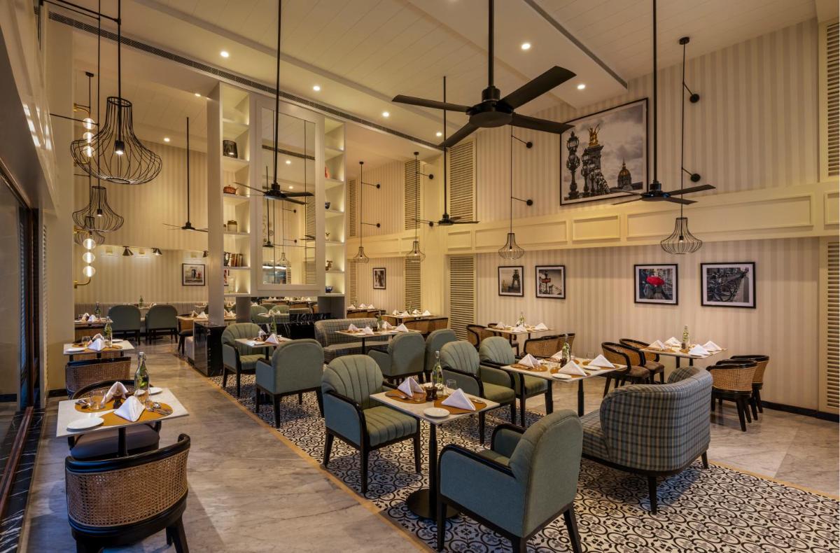 a restaurant with tables and chairs in a room at The Residency Towers Puducherry in Puducherry