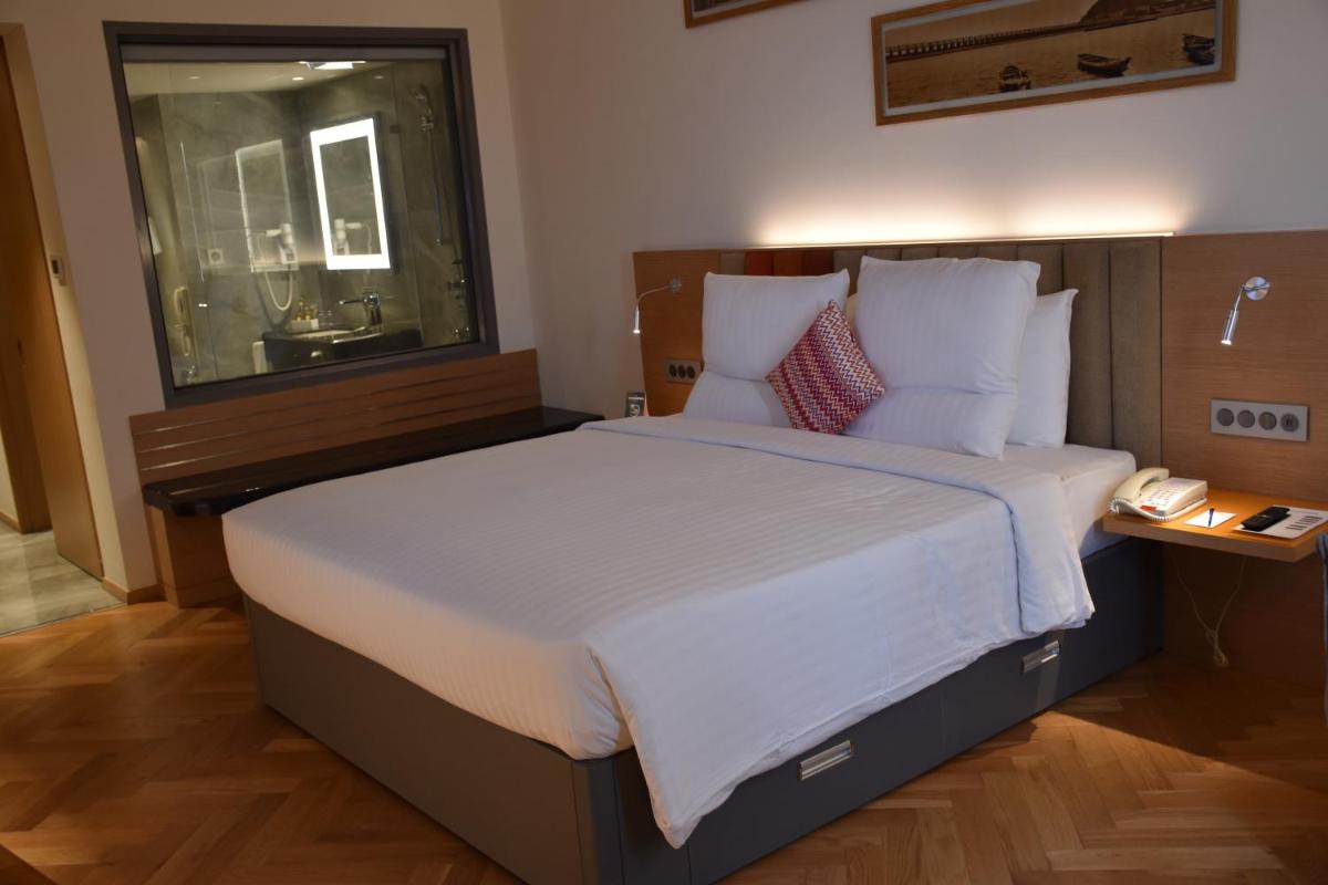 a bedroom with a large bed with white sheets and pillows at Novotel Vijayawada Varun in Vijayawāda