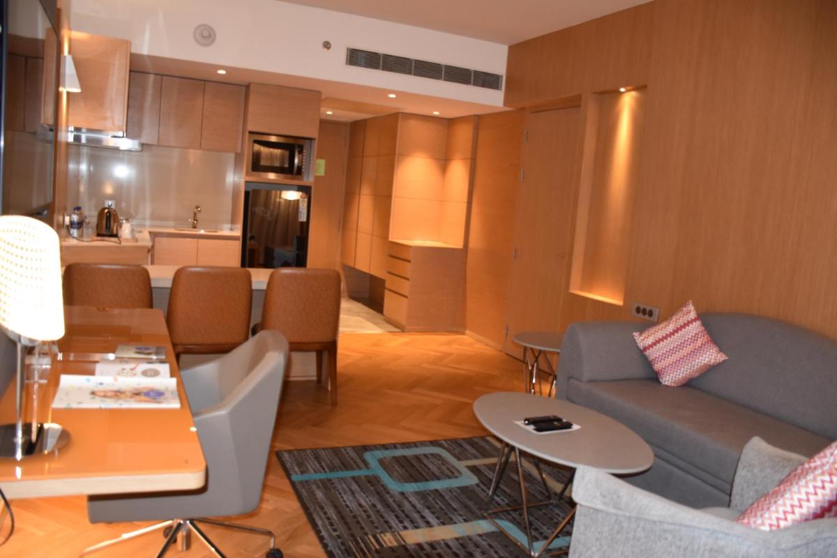 a living room with a couch and a kitchen at Novotel Vijayawada Varun in Vijayawāda