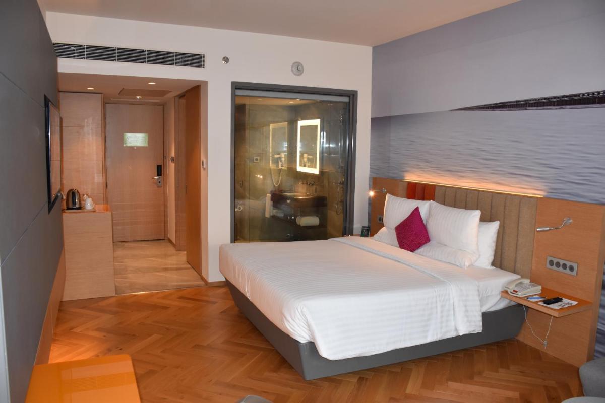 a bedroom with a large bed and a bathroom at Novotel Vijayawada Varun in Vijayawāda