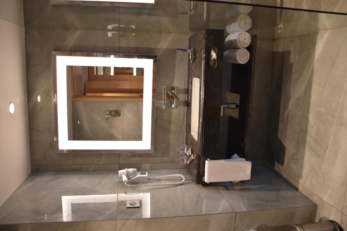 a bathroom with a sink and a mirror at Novotel Vijayawada Varun in Vijayawāda