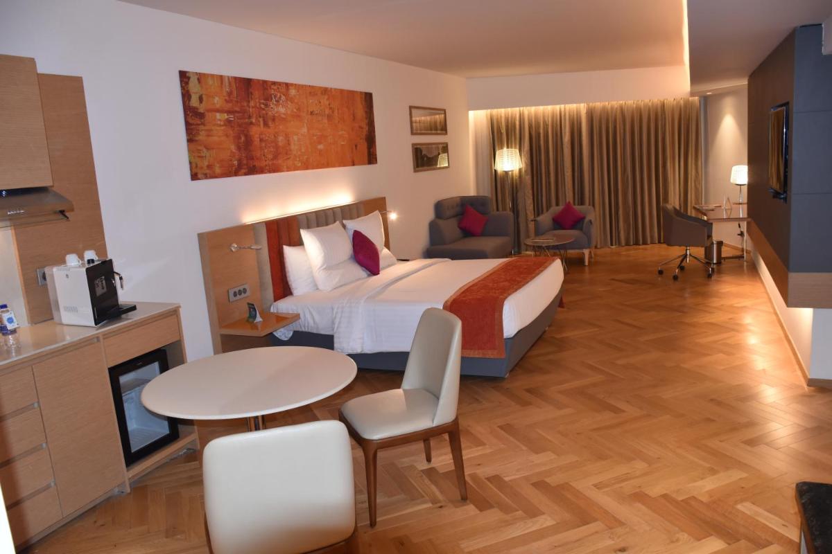 a hotel room with a bed and a table and chairs at Novotel Vijayawada Varun in Vijayawāda
