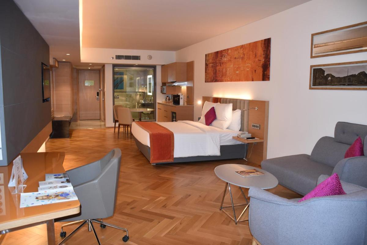 a hotel room with a bed and a table and chairs at Novotel Vijayawada Varun in Vijayawāda