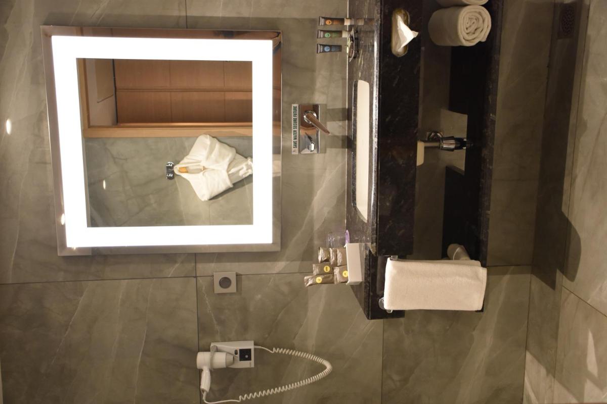a bathroom with a mirror and a sink at Novotel Vijayawada Varun in Vijayawāda