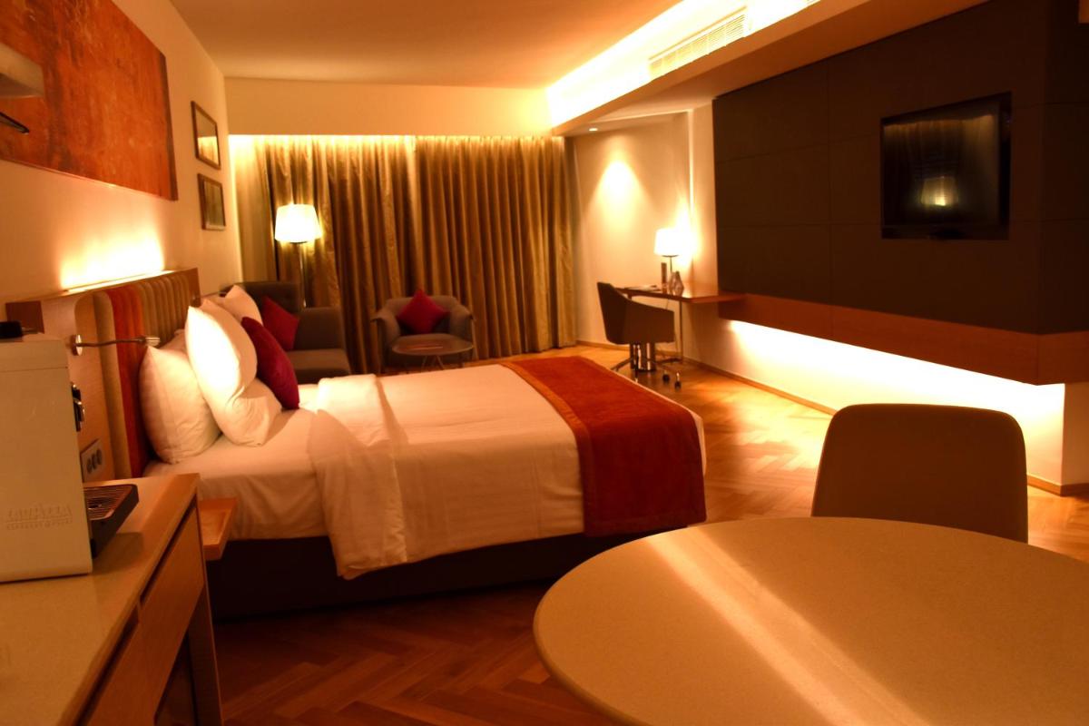 a hotel room with a bed and a table at Novotel Vijayawada Varun in Vijayawāda