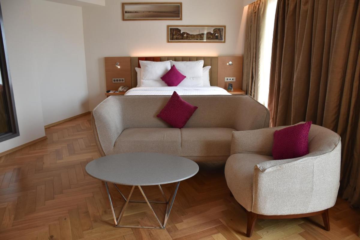 a hotel room with a couch and a bed at Novotel Vijayawada Varun in Vijayawāda