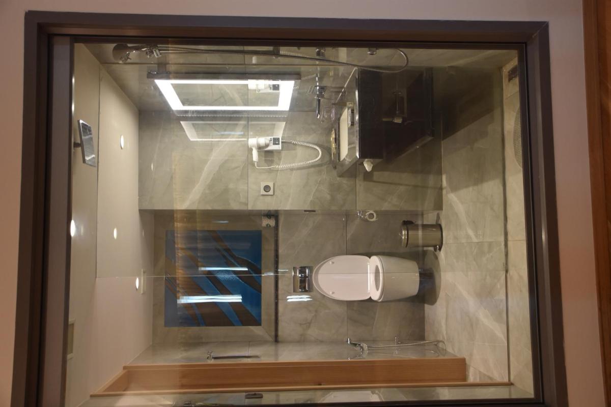a glass window of a bathroom with a toilet paper dispenser at Novotel Vijayawada Varun in Vijayawāda