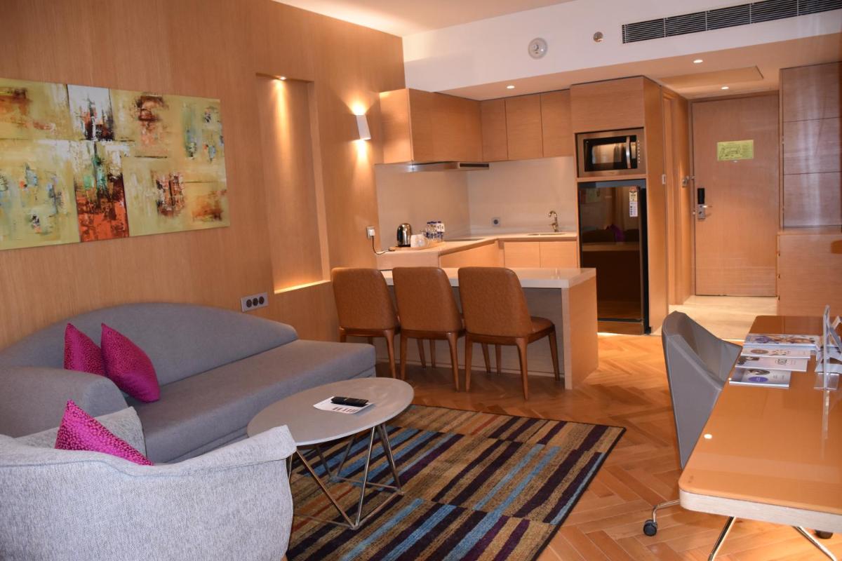 a living room with a couch and a kitchen at Novotel Vijayawada Varun in Vijayawāda