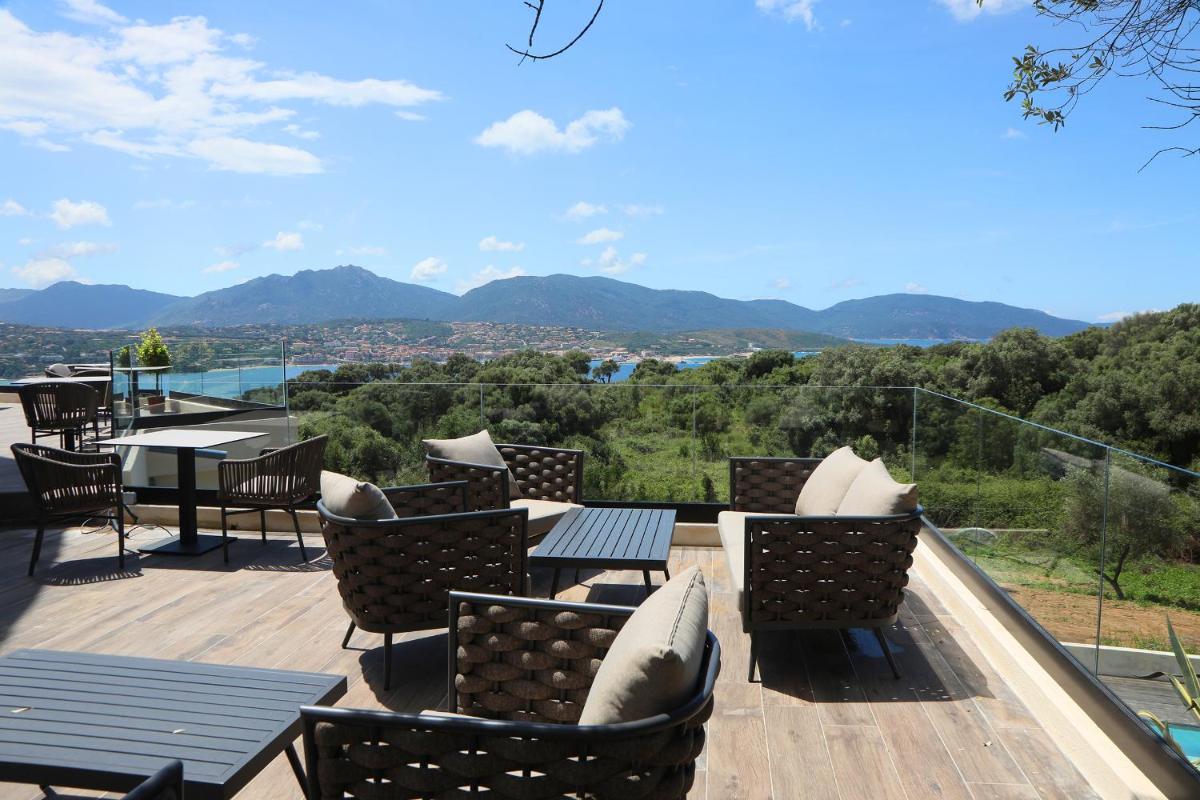 un patio avec chaises et tables et une vue sur les montagnes dans l'établissement L'Hostellerie du Moulin des Oliviers, à Olmeto