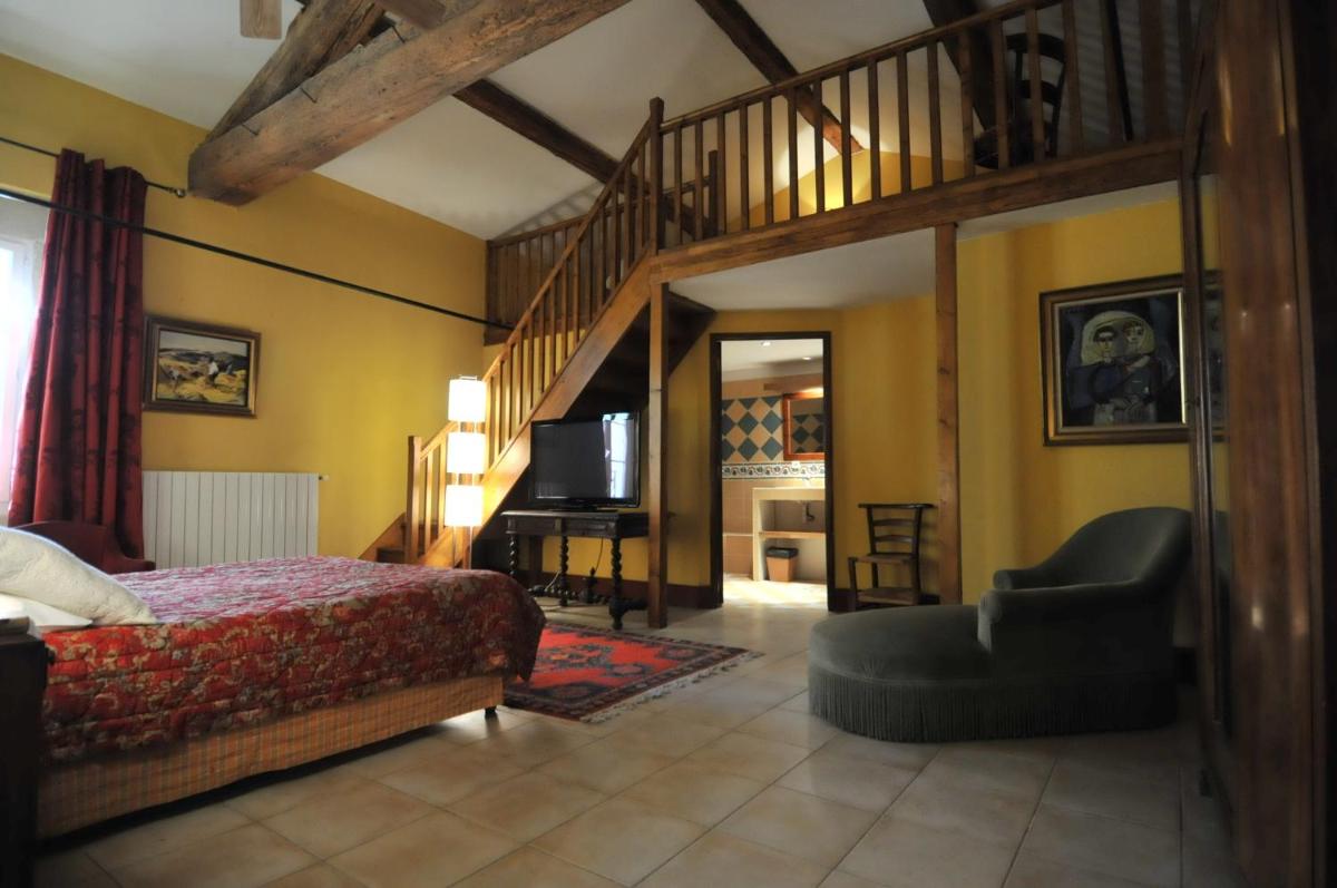 une chambre avec un grand lit et un escalier dans l'établissement Domaine du Grand Malherbes, à Aimargues