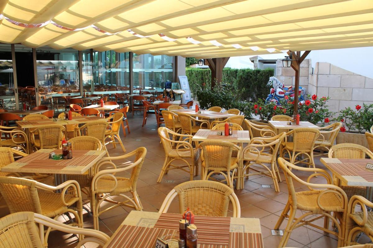Un patio al aire libre con mesas y sillas y un escritorio. en Apartaments Talayot, en Cala en Blanes