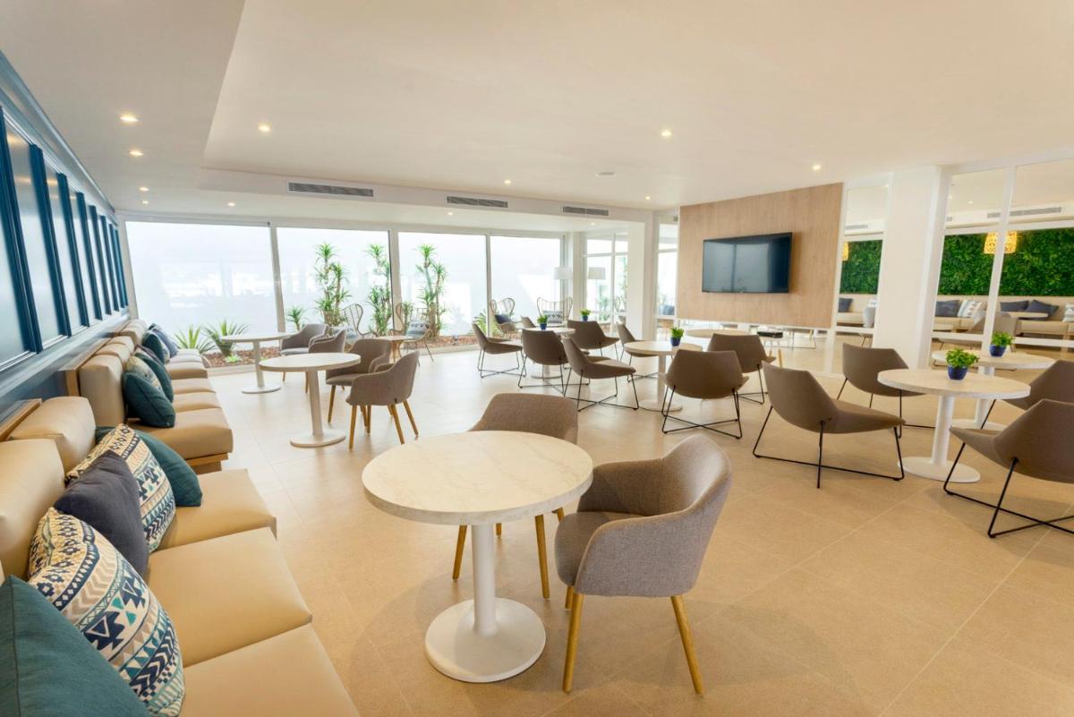 Un vestíbulo con un sofá, mesas y sillas. en Parque Nereida Suites Hotel, en Cala Ratjada