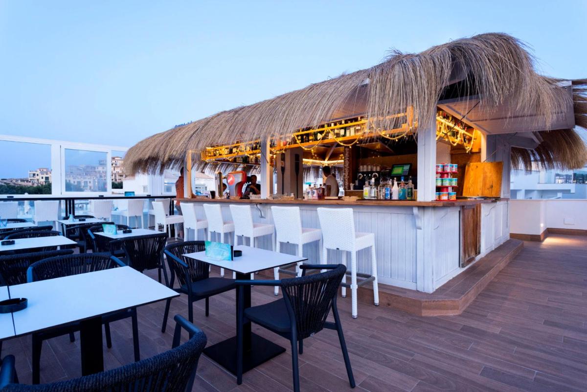 Un restaurante con mesas y sillas y un bar. en Parque Nereida Suites Hotel, en Cala Ratjada
