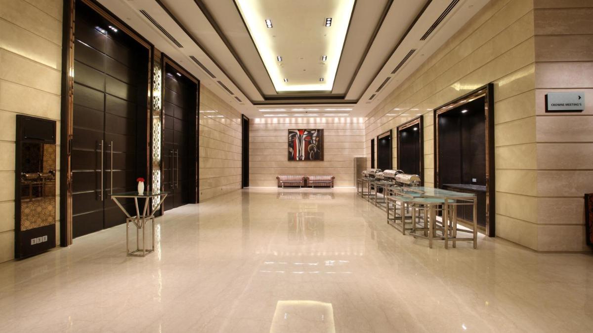 a lobby with tables and chairs in a building at Crowne Plaza New Delhi Rohini by IHG in New Delhi a lobby with tables and chairs in a building at Crowne Plaza New Delhi Rohini by IHG in New Delhi